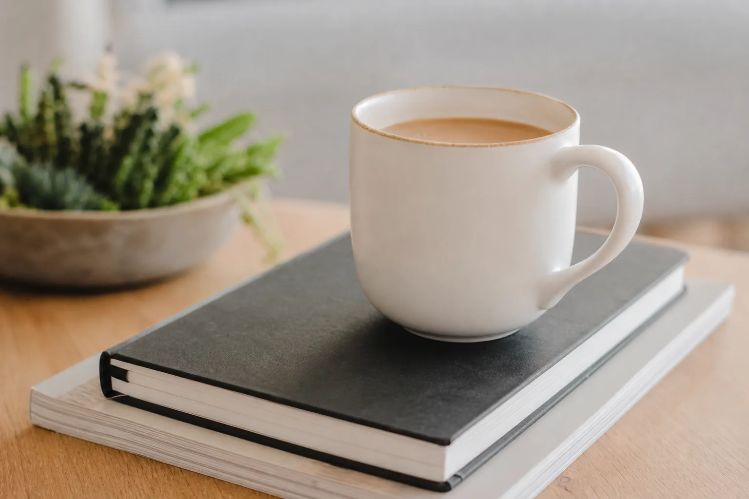 white ceramic mug with coffee on top of a planner