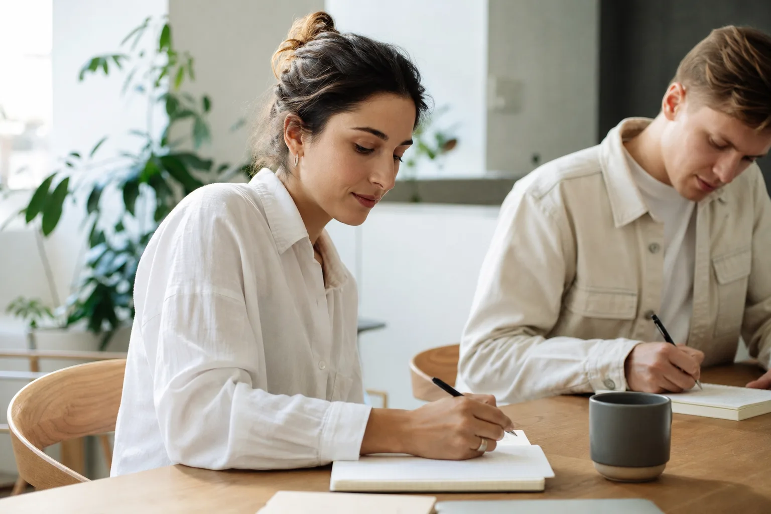 people sitting on chair in front of table while holding pens during daytime