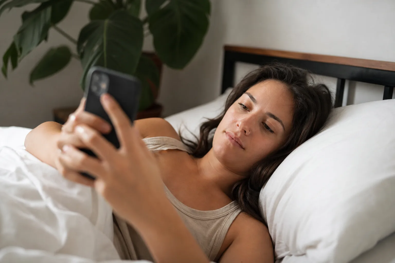 a person laying in bed holding a cell phone