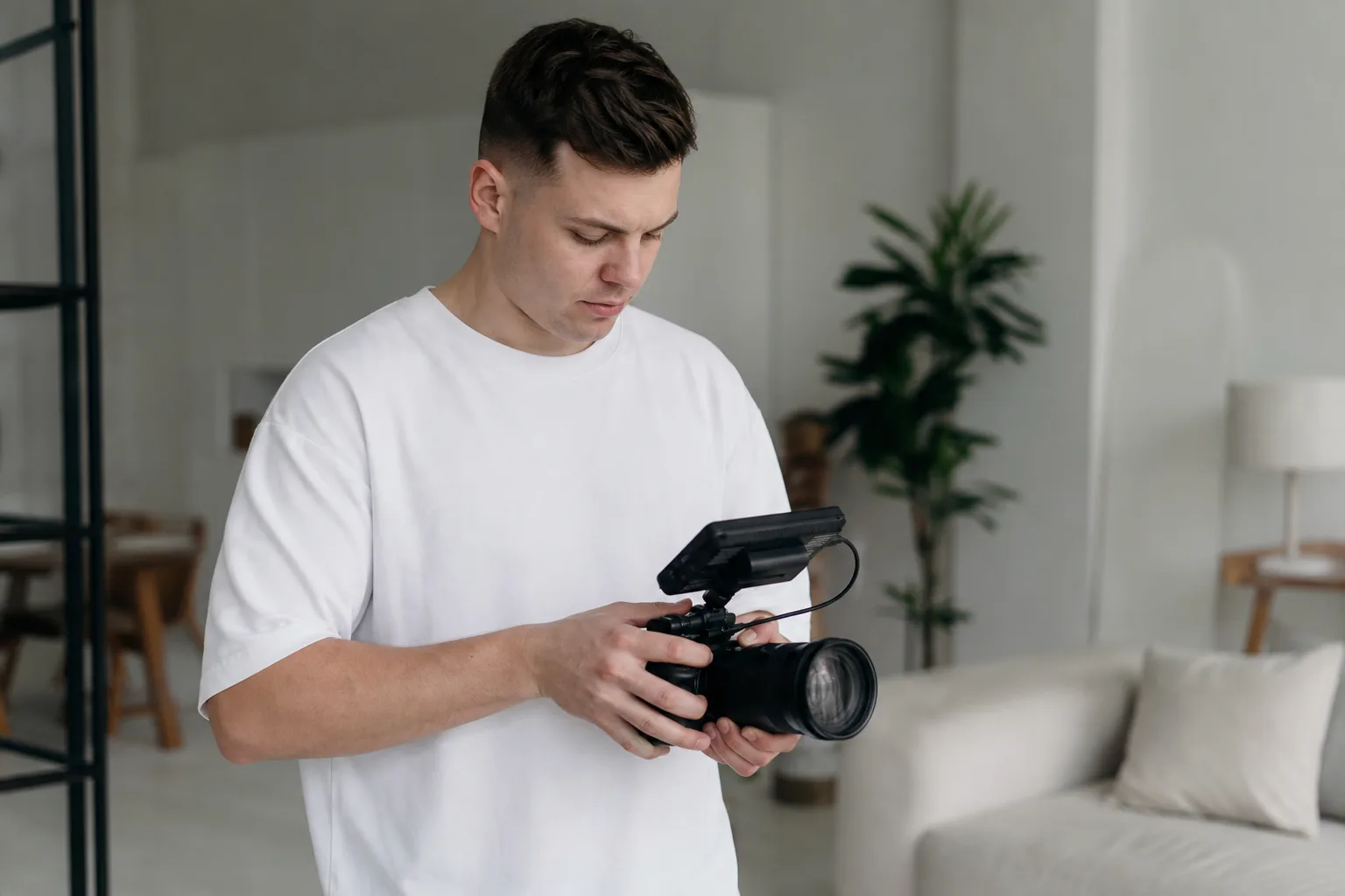 man in white t-shirt holding black video camera