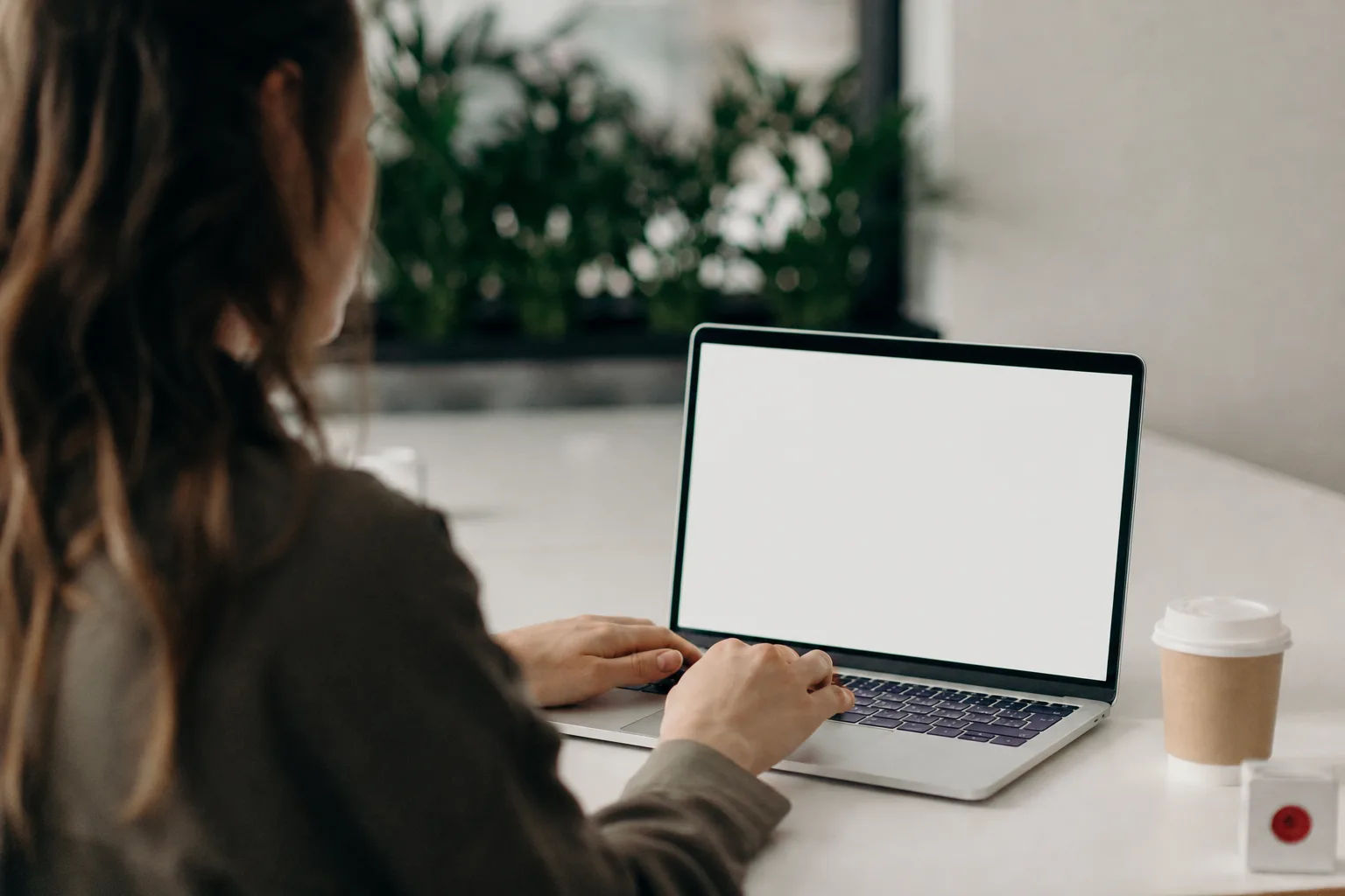 person using macbook pro on white table