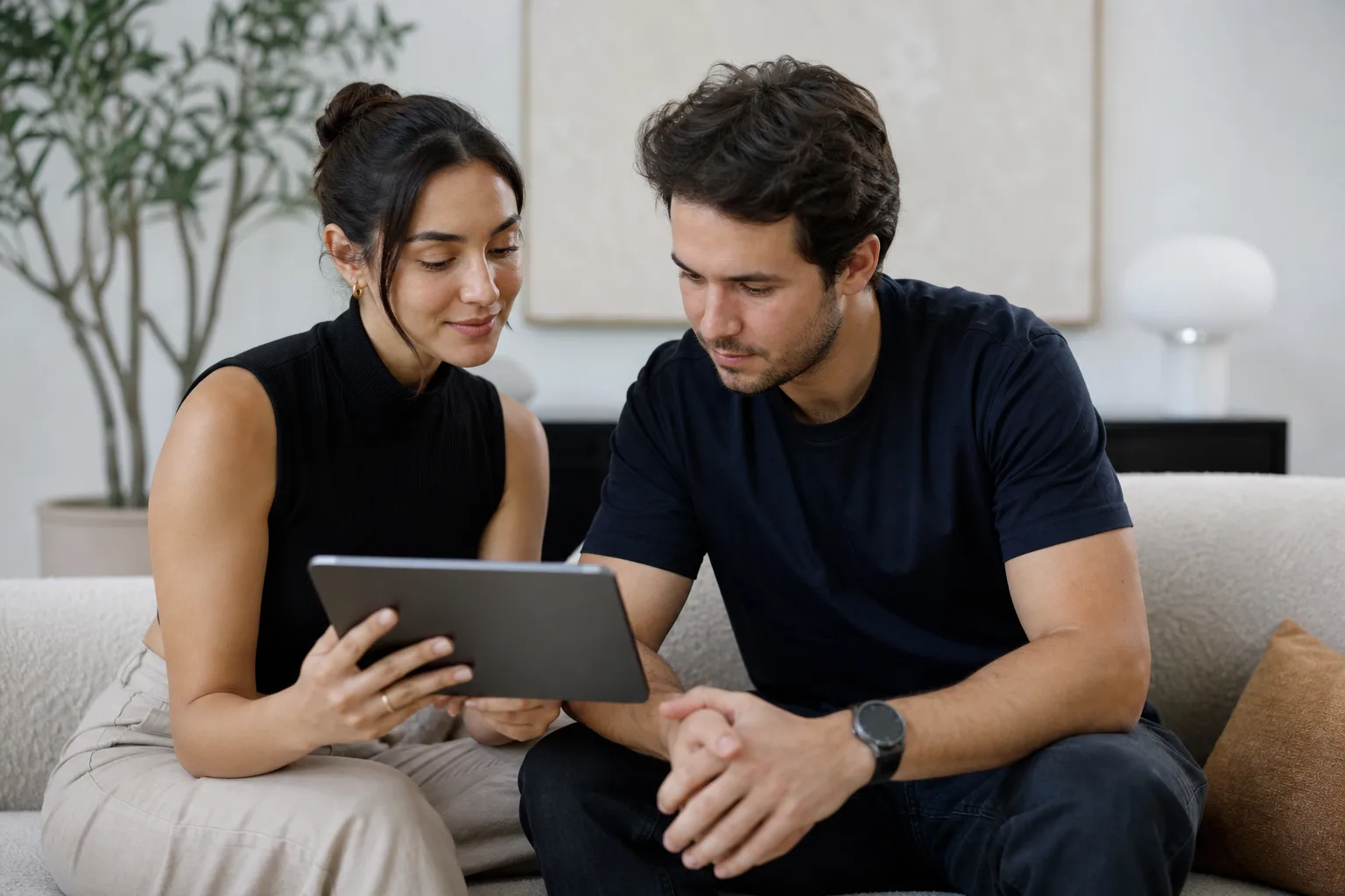 a woman showing a man something on a tablet