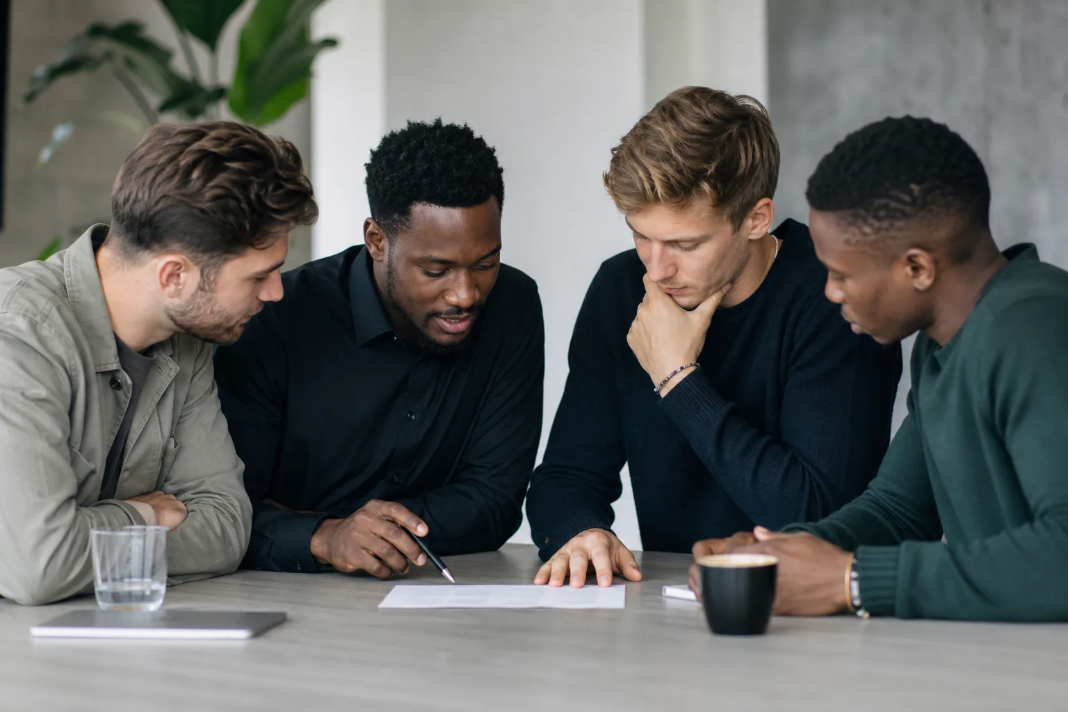 four men looking to the paper on table